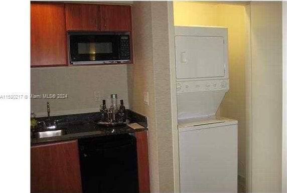 kitchen featuring sink, stacked washing maching and dryer, and black appliances