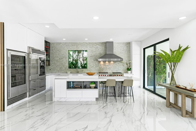 kitchen with white cabinets, wall chimney range hood, light tile floors, and tasteful backsplash