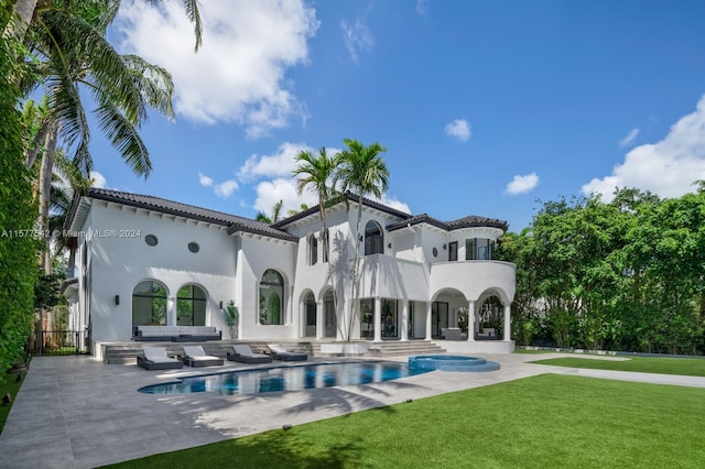 rear view of property with a patio area, a yard, and a balcony