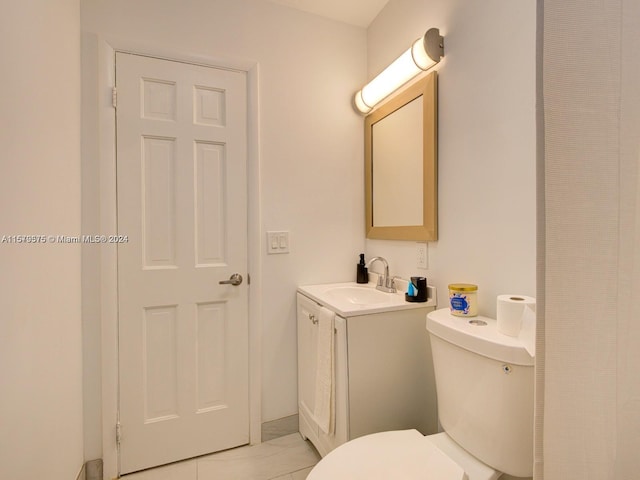 bathroom with toilet, tile floors, and vanity