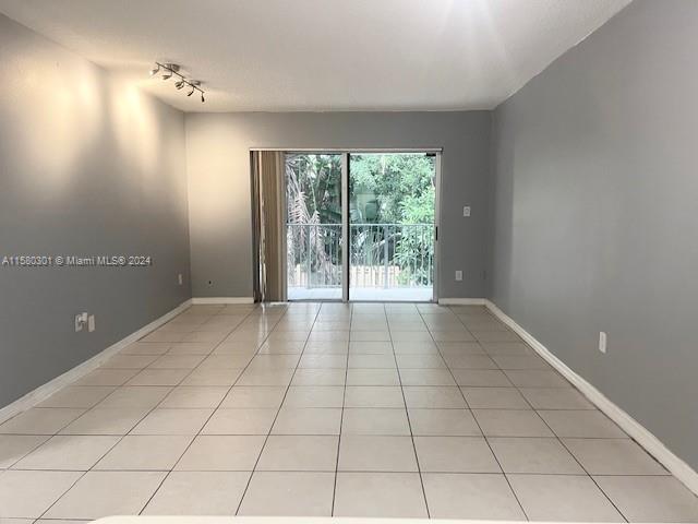 unfurnished room with light tile patterned floors and track lighting