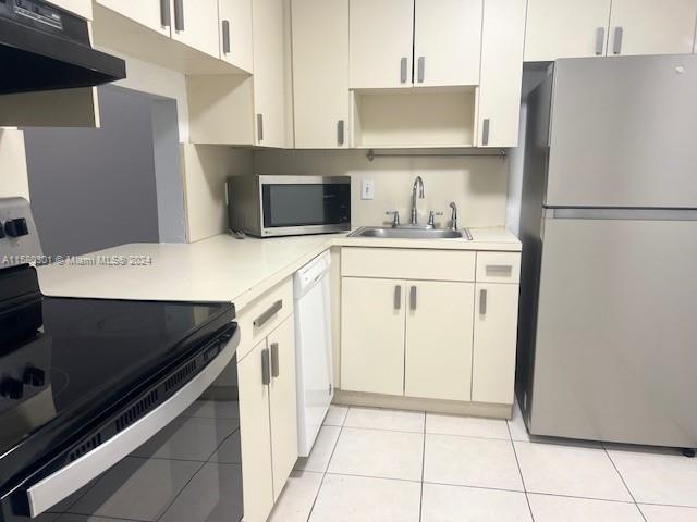 kitchen with white cabinets, light tile patterned floors, sink, and appliances with stainless steel finishes