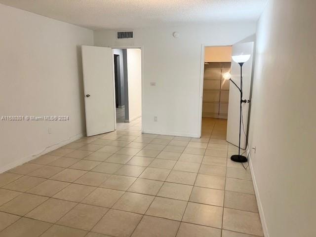 tiled empty room with a textured ceiling