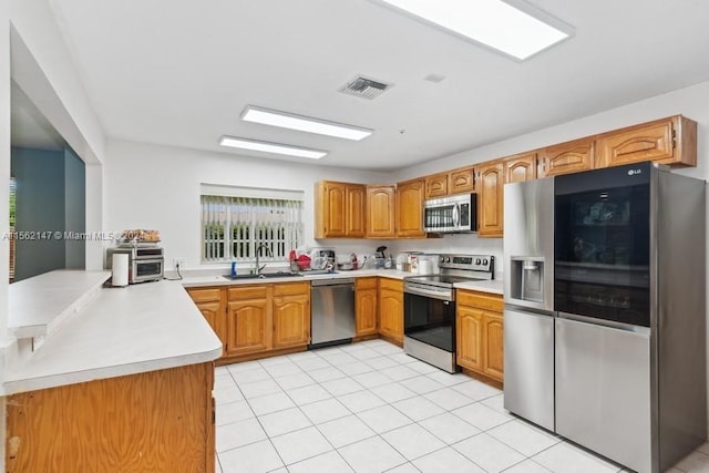 kitchen featuring sink, appliances with stainless steel finishes, kitchen peninsula, and light tile floors