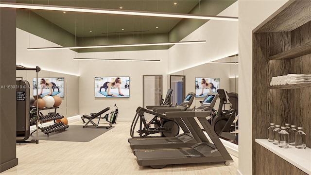 workout area featuring light hardwood / wood-style flooring and a high ceiling