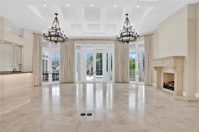 unfurnished living room featuring an inviting chandelier, french doors, a fireplace, and coffered ceiling