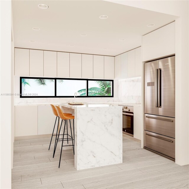 kitchen with light stone countertops, appliances with stainless steel finishes, white cabinetry, a kitchen breakfast bar, and sink