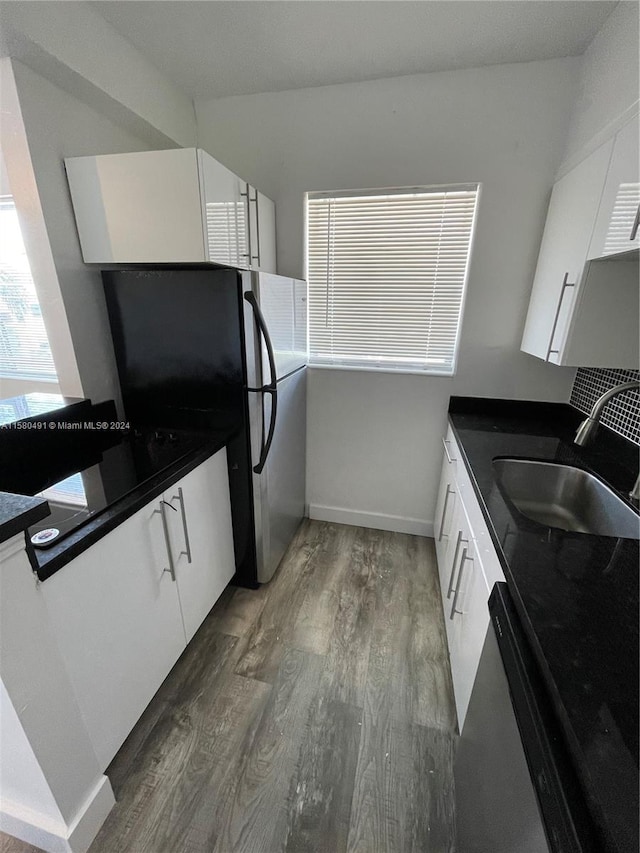 kitchen featuring sink, black fridge, hardwood / wood-style flooring, and white cabinetry