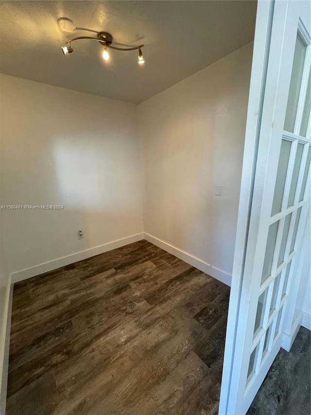 unfurnished room featuring rail lighting and dark hardwood / wood-style floors