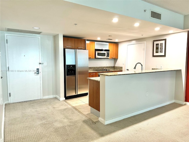 kitchen with light carpet, sink, stainless steel appliances, and light stone countertops