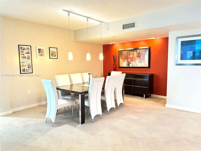 carpeted dining area featuring rail lighting