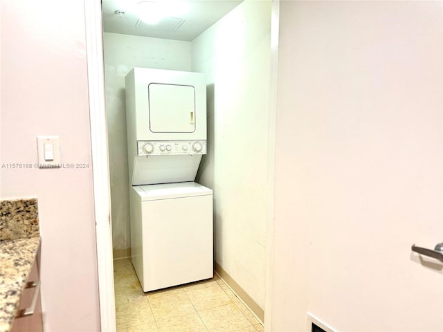 clothes washing area featuring stacked washing maching and dryer and light tile floors