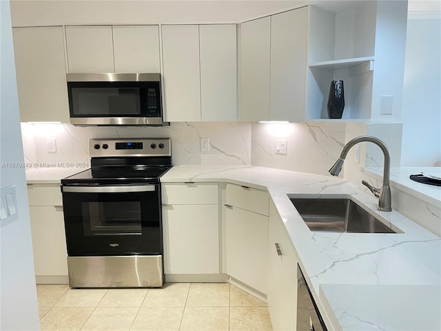 kitchen with light stone counters, appliances with stainless steel finishes, sink, tasteful backsplash, and light tile flooring