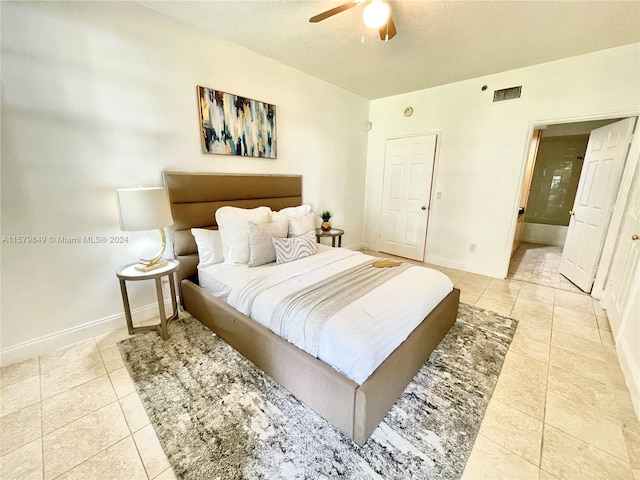 tiled bedroom with ceiling fan and a textured ceiling