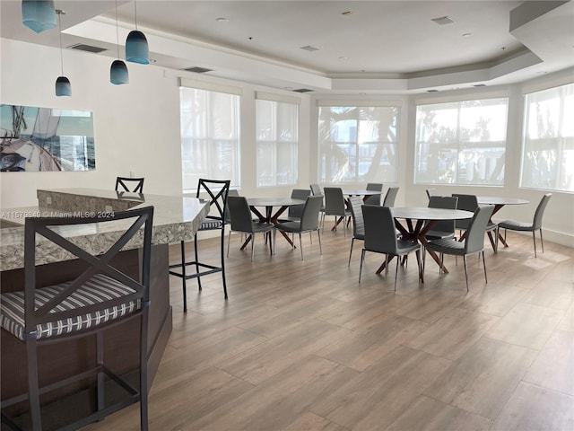 dining area with wood-type flooring and a raised ceiling