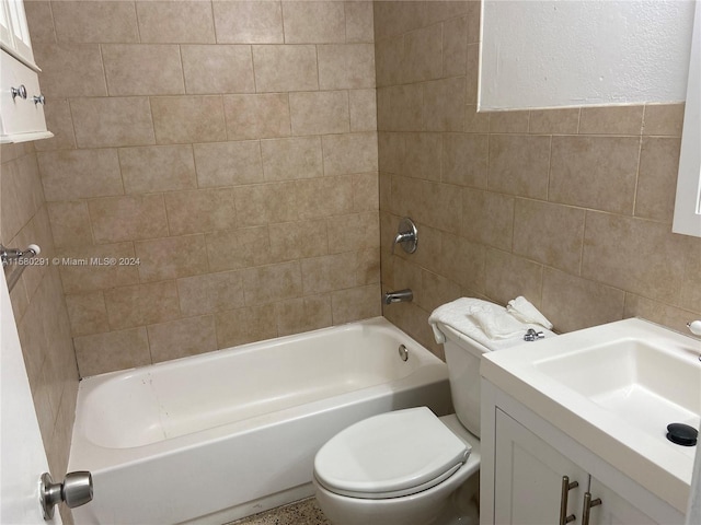 full bathroom with tile walls, toilet, tiled shower / bath combo, and vanity