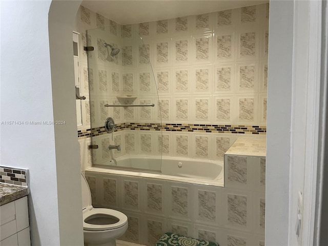 full bathroom featuring tiled shower / bath, toilet, and tile walls