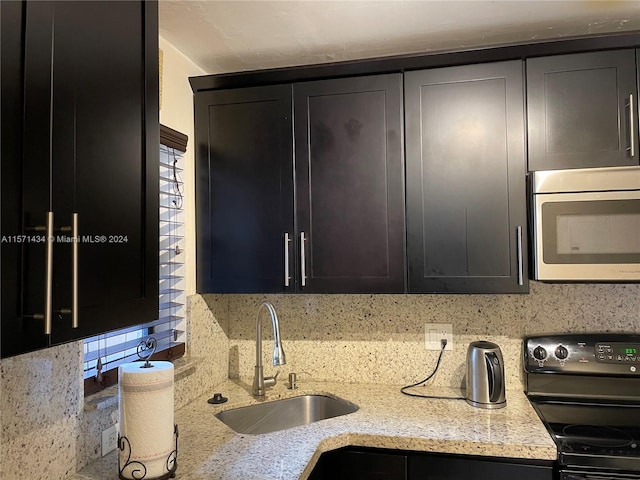 kitchen with backsplash, sink, light stone countertops, and black range with electric stovetop