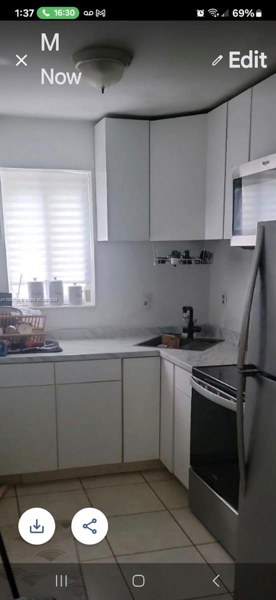 kitchen with white cabinets, stainless steel appliances, light tile patterned flooring, and sink