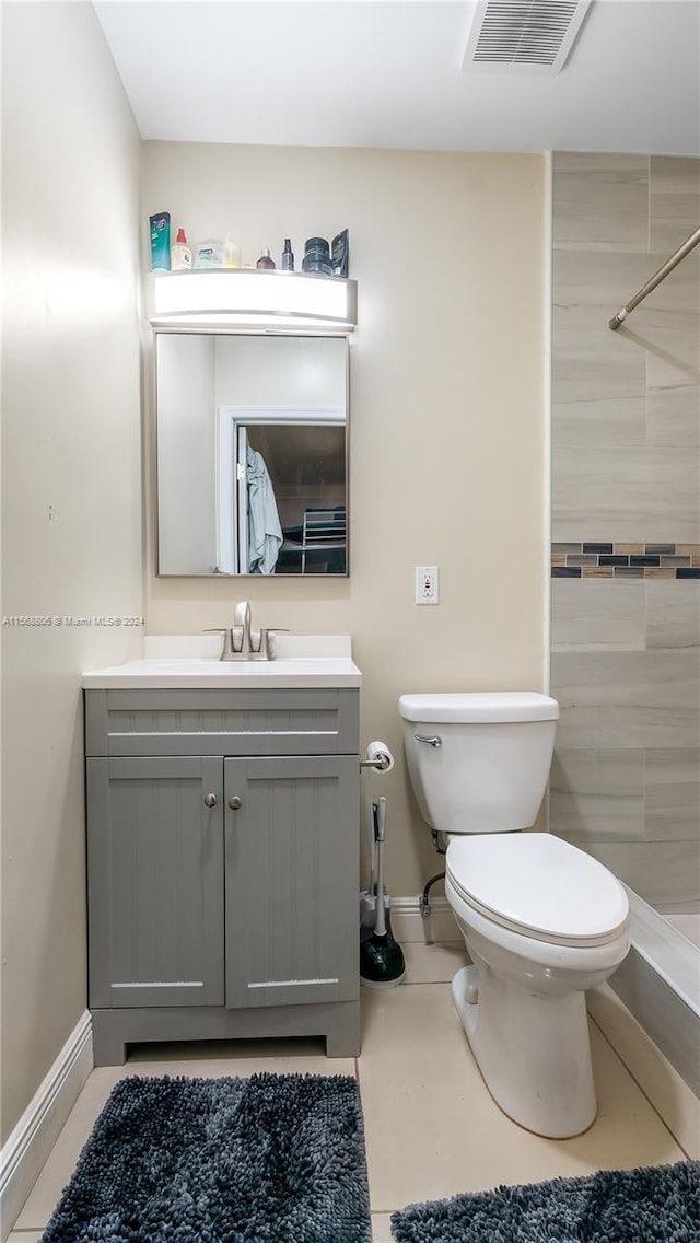 bathroom featuring tile floors, vanity, toilet, and tiled shower