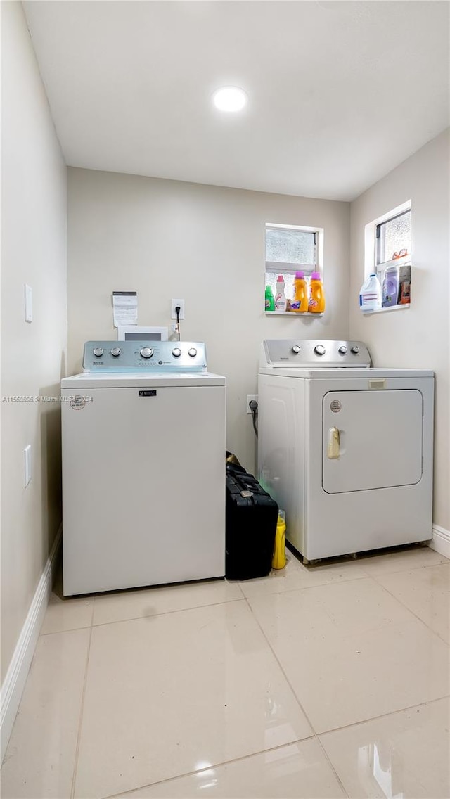 clothes washing area with independent washer and dryer and light tile floors