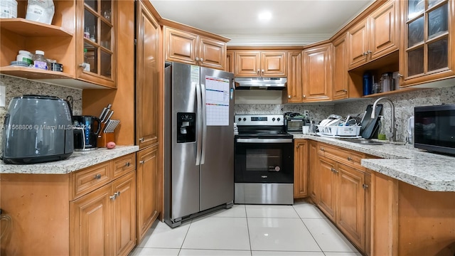 kitchen with light tile floors, sink, backsplash, stainless steel appliances, and light stone countertops