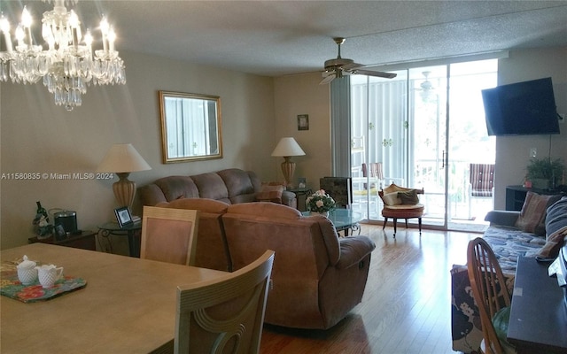 living room featuring hardwood / wood-style flooring, a healthy amount of sunlight, and ceiling fan with notable chandelier