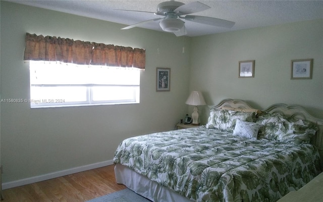 bedroom featuring ceiling fan, hardwood / wood-style flooring, and a textured ceiling