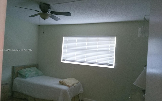 bedroom featuring a textured ceiling, multiple windows, and ceiling fan