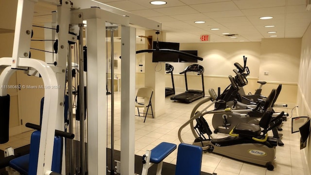 gym featuring a paneled ceiling and light tile patterned floors