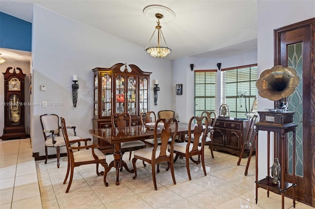 tiled dining space with a textured ceiling and a notable chandelier