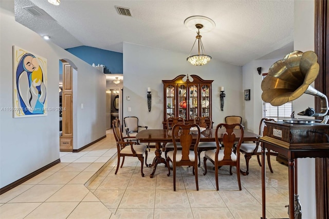 tiled dining space with lofted ceiling and a textured ceiling