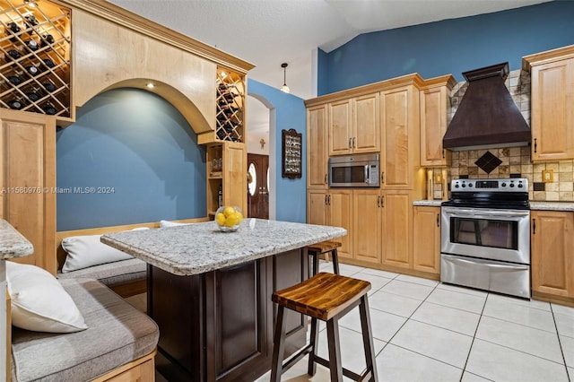 kitchen featuring a center island, custom range hood, vaulted ceiling, stainless steel appliances, and light tile patterned flooring