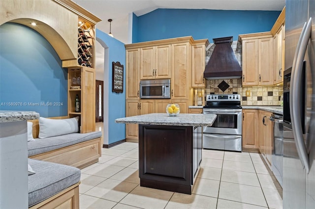 kitchen with a kitchen island, light brown cabinetry, premium range hood, appliances with stainless steel finishes, and light tile patterned flooring