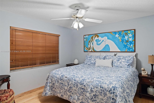 bedroom featuring ceiling fan, wood-type flooring, and a textured ceiling