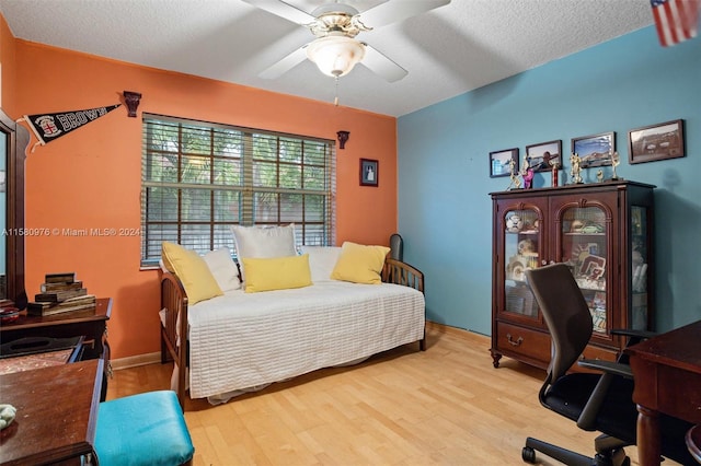 bedroom with a textured ceiling, ceiling fan, and light hardwood / wood-style floors