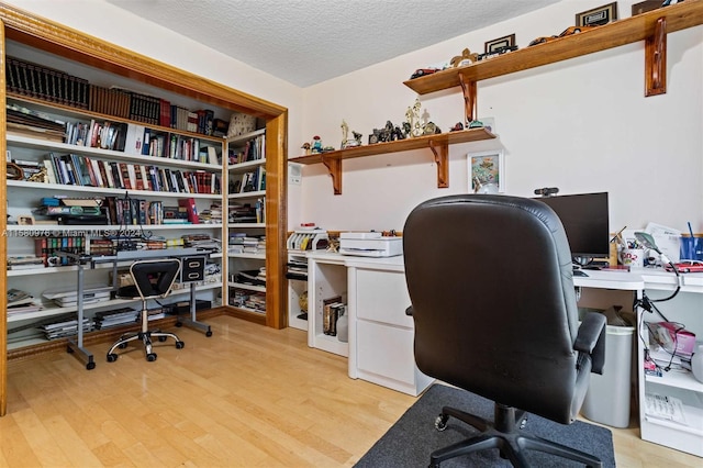 home office featuring light hardwood / wood-style floors and a textured ceiling