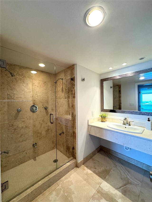 bathroom featuring a shower with door, tile flooring, and vanity with extensive cabinet space