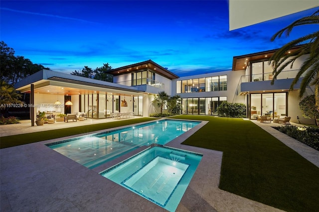 back of property at dusk featuring stucco siding, outdoor lounge area, a patio, and a balcony