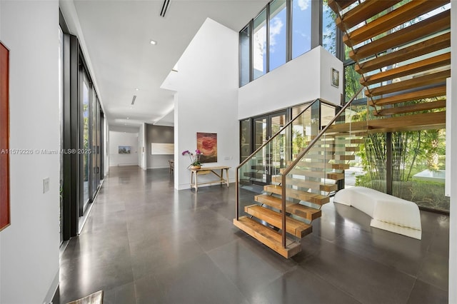staircase with a healthy amount of sunlight, a towering ceiling, and visible vents