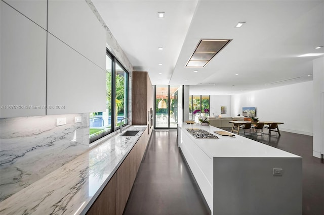 kitchen with white cabinets, stainless steel gas stovetop, a large island, and sink