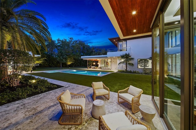 pool at dusk featuring a patio area and a yard