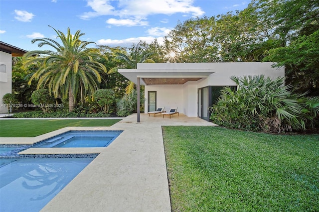 pool with a patio area, a yard, and an in ground hot tub