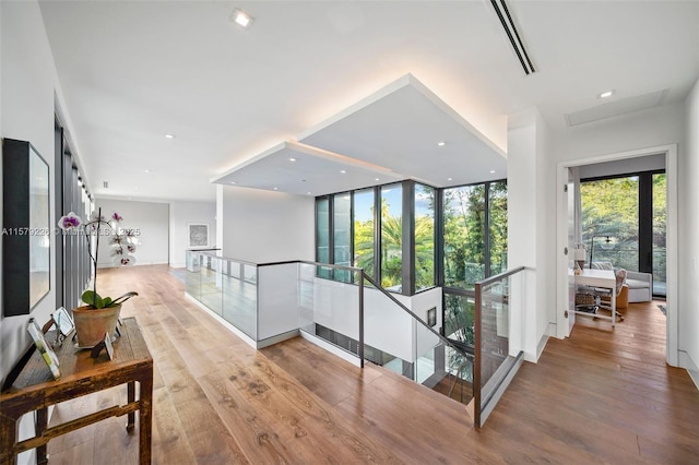 corridor with recessed lighting, wood finished floors, and an upstairs landing