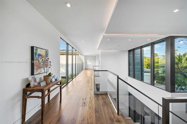corridor with floor to ceiling windows, wood finished floors, and recessed lighting