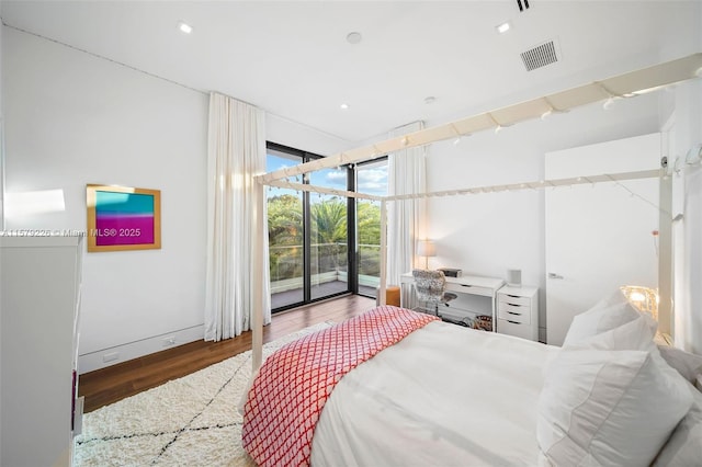 bedroom with expansive windows, wood finished floors, access to exterior, and visible vents