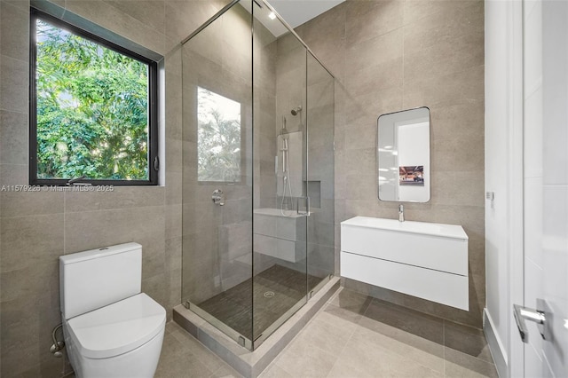 bathroom with a shower stall, tile patterned floors, vanity, tile walls, and toilet