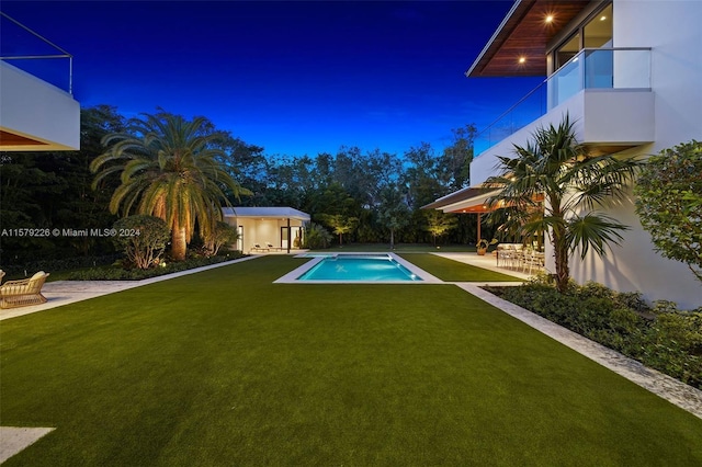 view of swimming pool featuring an outbuilding, a patio, and a lawn