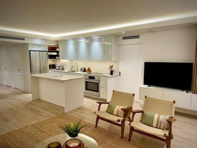 kitchen with light hardwood / wood-style floors, white cabinetry, stainless steel appliances, and a kitchen island