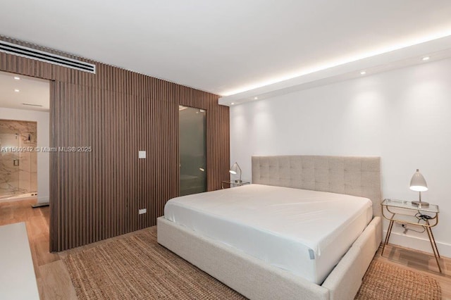 bedroom featuring light wood-type flooring and ensuite bath